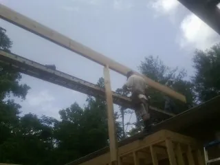 Carpenter setting a ridge beam over a new addition frame — Ice Dam Removal by Roofing Brothers in Saint Leonard