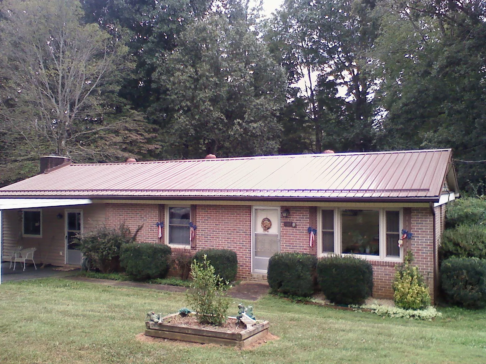Bronze metal roof on a brick ranch home with a carport in Saint Leonard