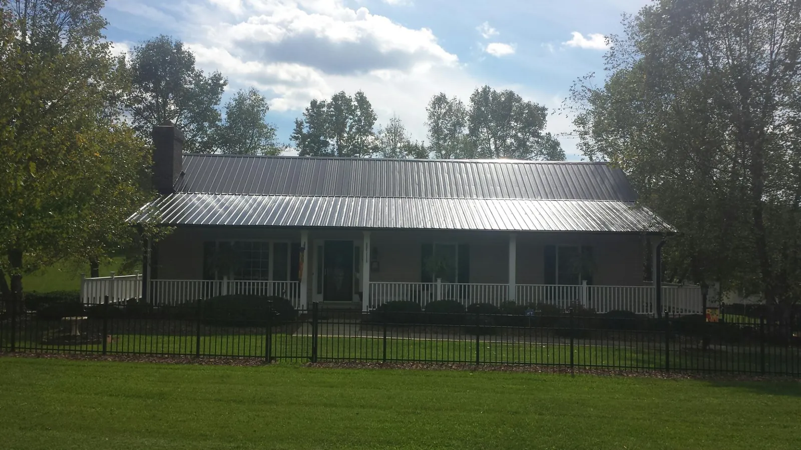Gray metal roof on a brick ranch with a full width front porch — Gutter Guard Installation work by our crew in Saint Leonard