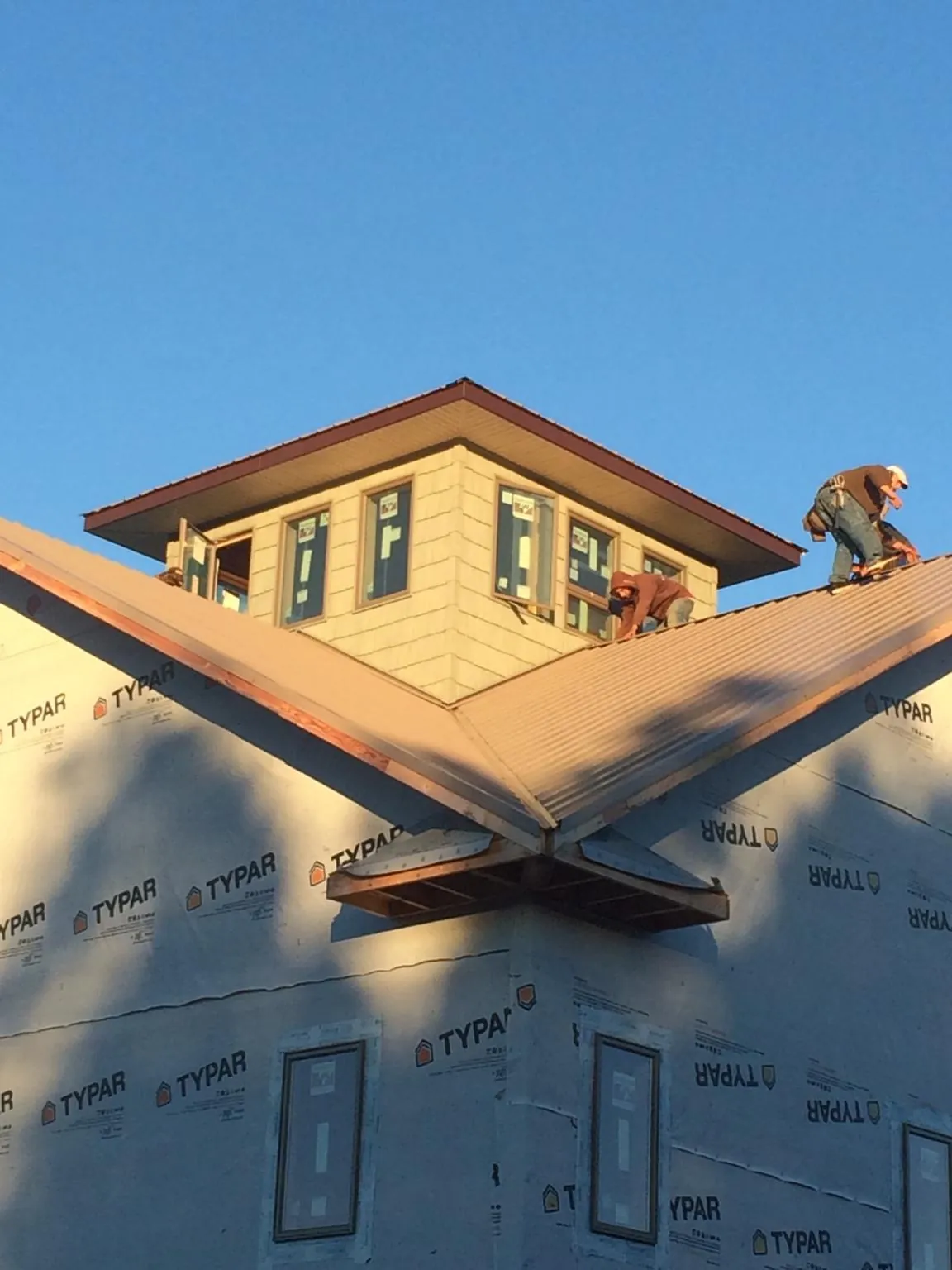 Roofers working around a rooftop cupola on a new metal roof at sunset — Roof Waterproofing in Saint Leonard by Roofing Brothers